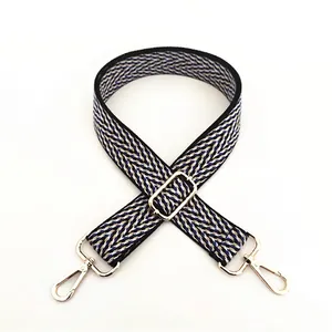 Detail of adjustable woven shoulder strap with blue V-pattern and gold metal lobster clasps