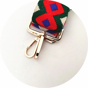 Close-up of ethnic colorful woven bag strap with geometric patterns and gold swivel hooks