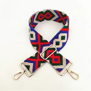 Close-up of ethnic geometric weave shoulder strap with gold metal buckles and lobster clips