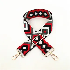 Close-up of ethnic geometric pattern strap with golden metal swivel hooks and buckles