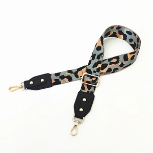 Dettaglio della tracolla regolabile con stampa leopardata, borchie dorate e ganci a moschettone