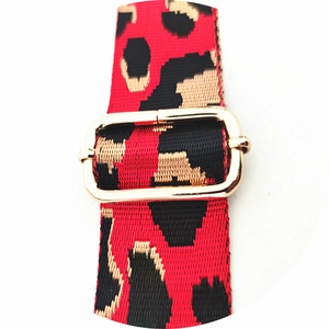 Detail of red and black leopard print bag strap with golden metal adjustment buckle
