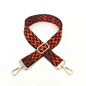 Detail of ethnic style woven strap with orange and black patterns and gold metal buckles