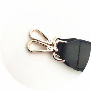 Detail of light gold lobster clasps and black leather stitching on adjustable strap