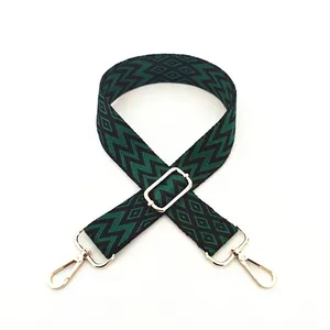 Close-up of adjustable woven strap with dark green geometric patterns and gold metal buckles