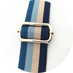 Close-up of adjustable woven shoulder strap with blue stripes and gold metal buckle
