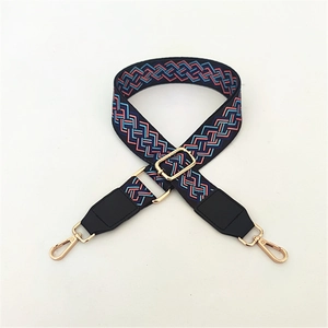 Close-up of adjustable woven shoulder strap with geometric patterns and golden metal clasps