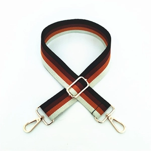 Macro shot of adjustable striped canvas bag strap with golden hardware and rotating hooks