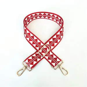 Detail view of red and white geometric woven shoulder strap with gold metal buckles