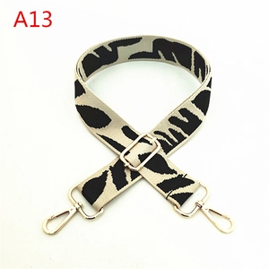 Detail of adjustable woven bag strap with black and white zebra pattern and gold metal hooks