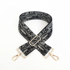 Détail d'une large bandoulière réglable avec motif serpent gris et boucles dorées chic