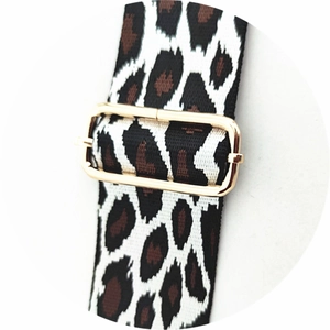 Close-up of leopard print webbing bag strap with adjustable gold metal buckle hardware