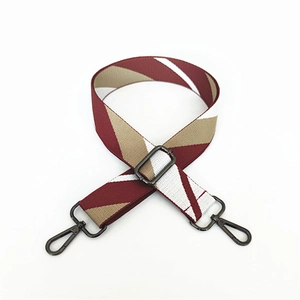Detail of adjustable crossbody bag strap with red and white diagonal stripes and black hooks