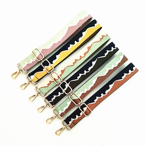 Detail view of adjustable canvas bag straps with wave patterns and gold metal hooks