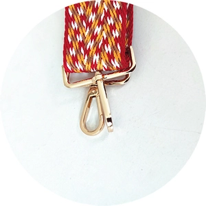 Detailed close-up of wide woven bag strap with jacquard pattern and gold metal swivel hook