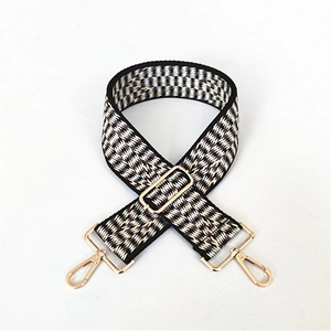 Detail of adjustable wide jacquard bag strap with herringbone weave and gold metal clips