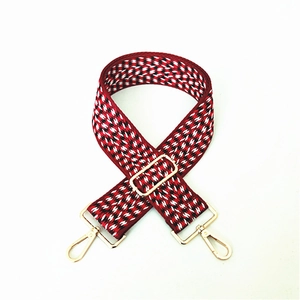 Adjustable wide woven shoulder strap with red white geometric pattern and gold buckles