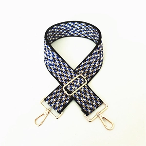 Detail of adjustable woven bag strap with colorful geometric pattern and gold metal hooks