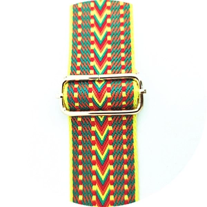 Close-up of adjustable woven bag strap with red, yellow, green wave patterns and gold buckle