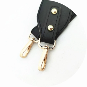 Detail of the golden lobster clasp and rivets on a black leather adjustable bag strap