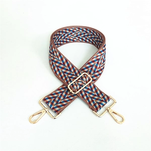 Detail of adjustable wide woven bag strap with brown blue jacquard pattern and gold hooks