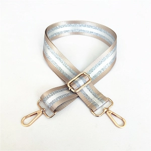 Detail of adjustable beige woven strap with silver metallic stripes and gold metal clips