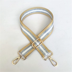 Detail of adjustable khaki strap with silver stripes and golden metal clasps