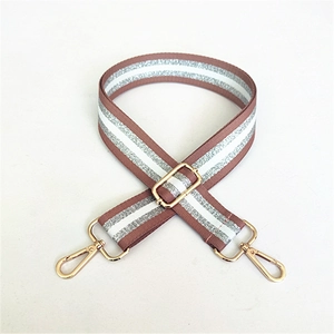 Close-up of adjustable brown woven bag strap with silver glitter stripes and gold buckles