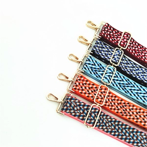 Detailed view of woven adjustable bag straps with ethnic patterns and gold metal hooks