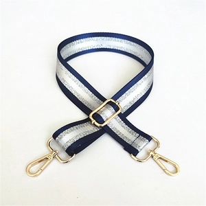 Detail of adjustable navy woven strap with silver glitter stripes and gold metal buckles