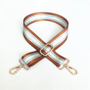 Detail of adjustable brown orange striped bag strap with gold metal hooks and glitter yarn