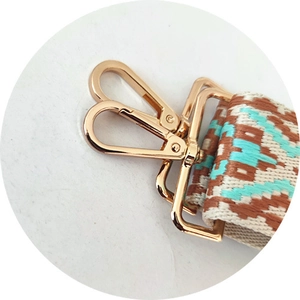 Detailed close-up of light gold lobster clasp and ethnic geometric woven strap