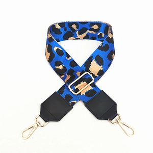 Detail of leopard print polyester strap with golden swivel clasps and black leather ends
