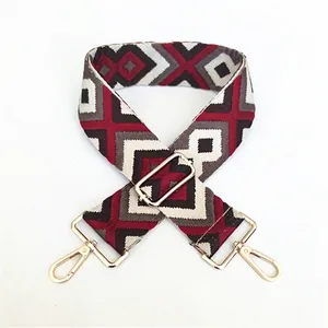 Close-up of geometric red and grey jacquard bag strap with gold metal lobster clasps