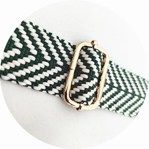 Detail of green and white checkered woven strap with golden adjustable buckle