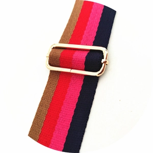 Detail view of adjustable wide striped shoulder strap with gold metal buckle for bags