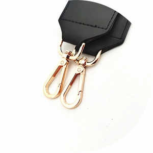 Macro detail of black leather bag strap with stitching and gold lobster swivel clasps