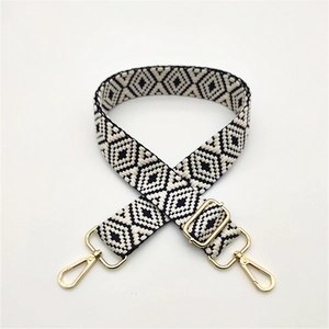 Close-up of adjustable woven shoulder strap with black and white diamond patterns and gold hooks