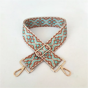 Close-up of ethnic woven strap with brown green geometric pattern and gold metal hooks