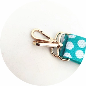 Close-up of adjustable teal polka dot bag strap with premium gold metal lobster clasp