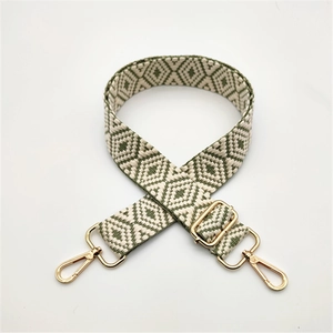 Detail of green geometric woven bag strap with adjustable length and gold metal clasp