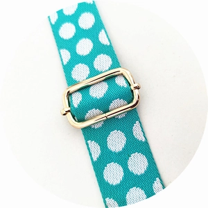 Detailed view of turquoise polka dot strap featuring a golden metal adjustment buckle