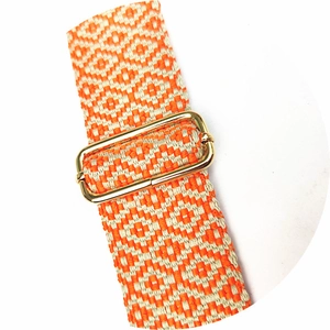 Detail of adjustable orange and beige woven bag strap with geometric diamond patterns