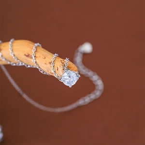 Macro shot of a single round zircon pendant necklace on a rustic wood branch