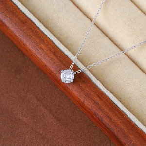 Close-up of a silver necklace featuring a four-prong set round zircon pendant in a box
