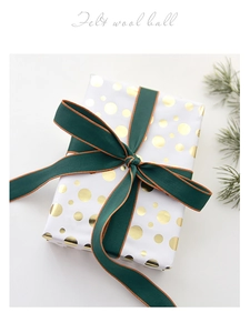 Close-up of elegant Christmas gift box with dark green gold-edged ribbon and pine needles