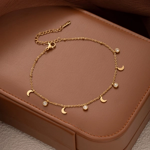 Detail of gold ankle chain featuring crescent moons and sparkling round zircon charms