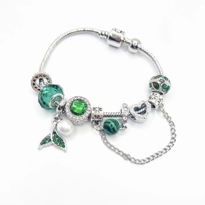 Silver snake chain bracelet featuring green crystal beads and a pearl fish tail charm