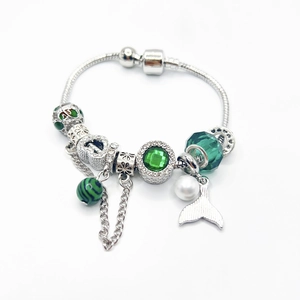 Detailed view of silver snake chain bracelet with green charms and pearl fish tail pendant