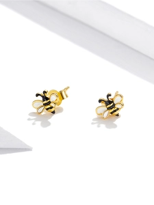 Macro detail of gold-plated silver bee stud earrings with black and white enamel wings